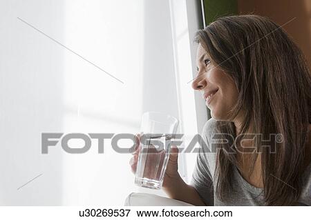 Woman drinking water at home View Large Photo Image Stock Photo - Woman drinking water at home. Fotosearch