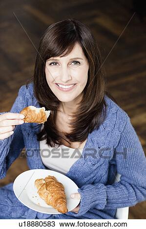 Stock Image - Woman eating croissant. Fotosearch