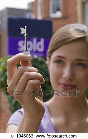 Stock Image - Woman first time buyer holds up door key. Fotosearch