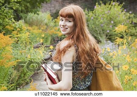 Woman holding books walking through park View Large Photo Image Stock Photography - Woman holding books walking through park. Fotosearch
