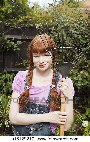 Woman holding grass rake in garden View Large Photo Image Stock Photo - Woman holding grass rake in garden. Fotosearch