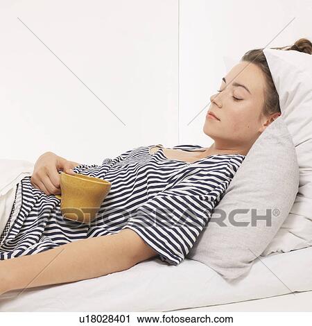 Woman in bed holding a mug View Large Photo Image Stock Image - Woman in bed holding a mug. Fotosearch