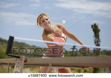 Stock Image - Woman in bikini playing table tennis. Fotosearch