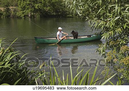 Stock Image - Woman in canoe with dog. Fotosearch