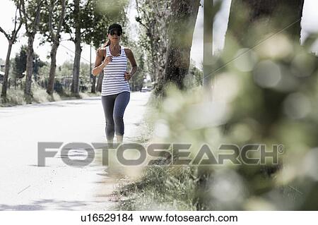 Woman jogging on a street View Large Photo Image Picture - Woman jogging on a street. Fotosearch