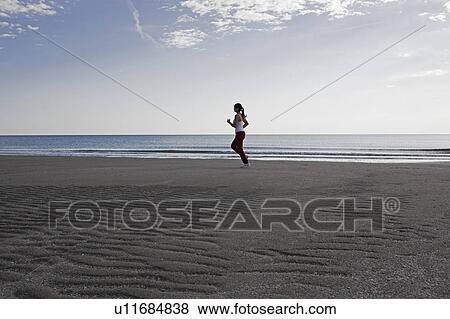 Stock Photo - Woman jogging on the beach. Fotosearch