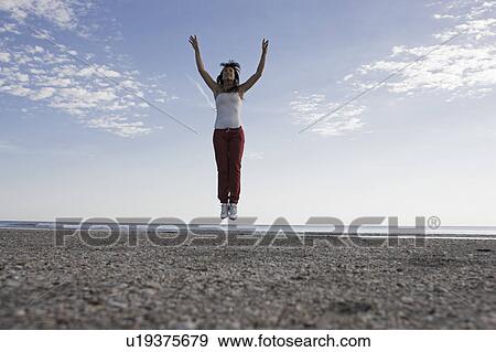Stock Photo - Woman jumping on the beach. Fotosearch