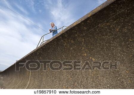 Woman leaning on rail above wall View Large Photo Image Stock Image - Woman leaning on rail above wall. Fotosearch