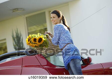 Stock Photo - Woman lifting grocery from electric car. Fotosearch