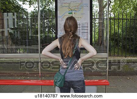 Stock Photo - Woman looking at bus time table. Fotosearch