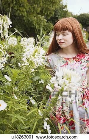 Stock Image - Woman looking at flowers in park. Fotosearch