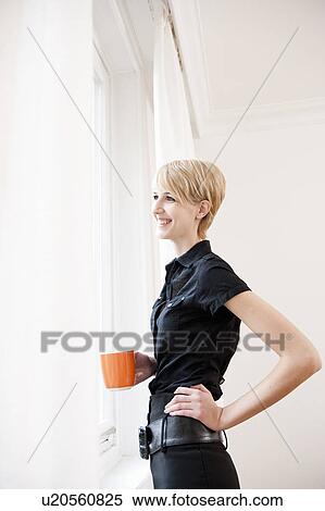 Woman looking out a window, smiling View Large Photo Image Stock Photography - Woman looking out a window, smiling. Fotosearch