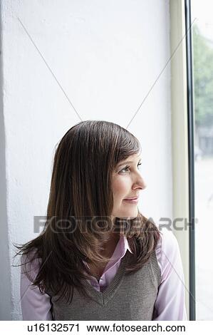 Stock Image - Woman looking out window portrait. Fotosearch