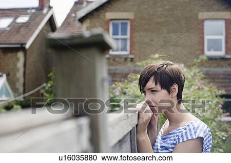 Stock Image - Woman looking over fence. Fotosearch