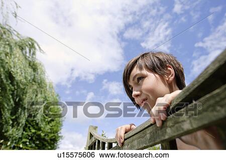 Woman looking over fence View Large Photo Image Stock Photograph - Woman looking over fence. Fotosearch