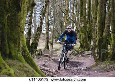 Stock Photo - Woman mountain biking in woods. Fotosearch