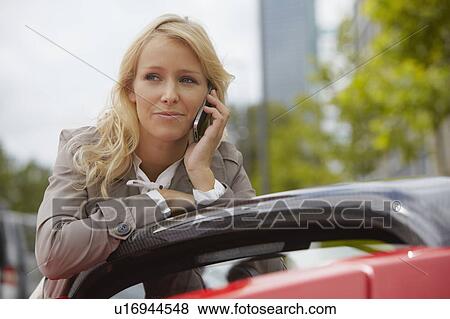 Woman on her phone, electric sports ca View Large Photo Image Stock Photo - Woman on her phone, electric sports ca. Fotosearch
