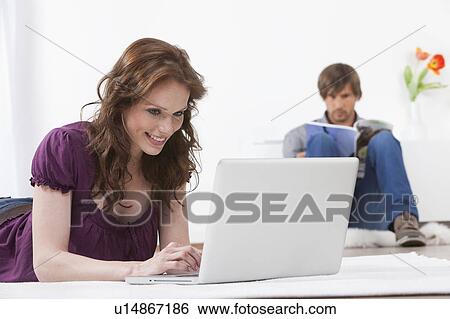 Woman on laptop while man reads View Large Photo Image Stock Photograph - Woman on laptop while man reads. Fotosearch
