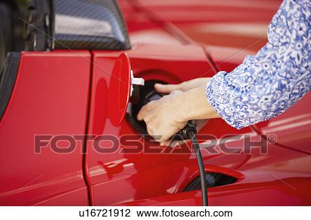 Woman plugging in her electric car View Large Photo Image Stock Image - Woman plugging in her electric car. Fotosearch