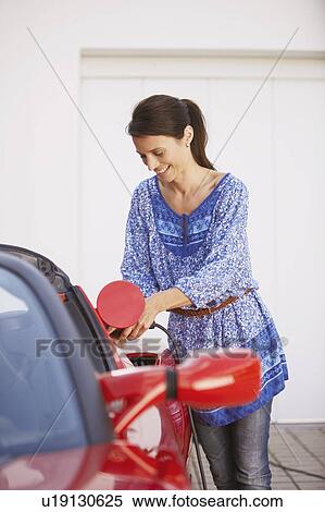 Stock Photography - Woman plugging in her electric car. Fotosearch
