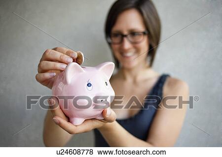 Woman putting coin into piggybank View Large Photo Image Stock Photo - Woman putting coin into piggybank. Fotosearch