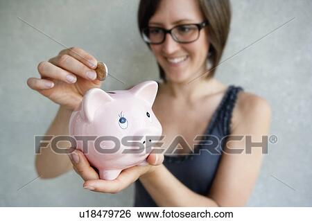 Woman putting coin into piggybank View Large Photo Image Stock Photograph - Woman putting coin into piggybank. Fotosearch