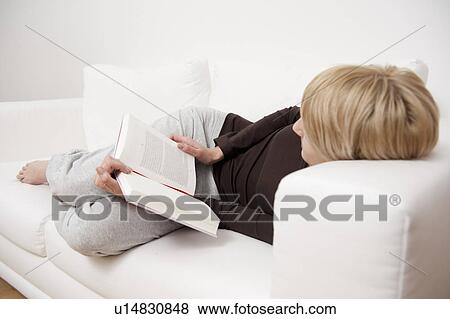 Woman reading a book on sofa View Large Photo Image Stock Photo - Woman reading a book on sofa. Fotosearch