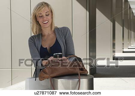 Stock Photo - Woman reading message on mobile phone. Fotosearch