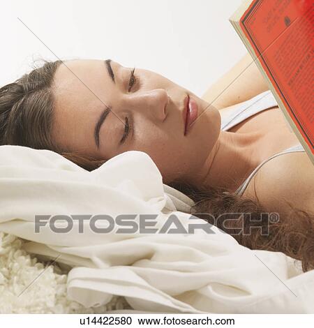 Stock Image - Woman reclined reading book. Fotosearch