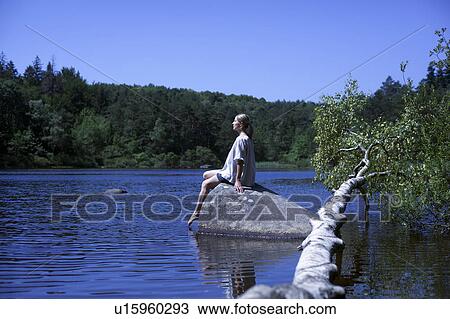 Stock Image - Woman relaxing by a lake. Fotosearch