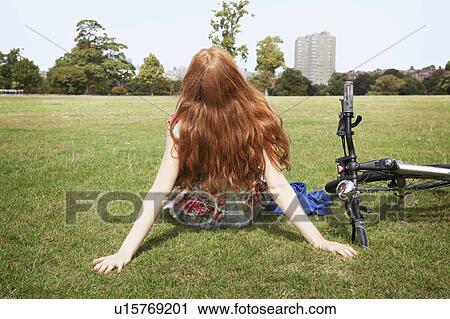Woman resting in grass next to bike View Large Photo Image Stock Image - Woman resting in grass next to bike. Fotosearch
