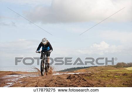 Woman riding mountain bike through mud View Large Photo Image Stock Photography - Woman riding mountain bike through mud. Fotosearch