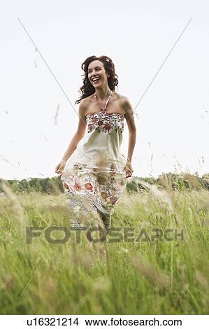Picture - Woman running through wild meadow. Fotosearch