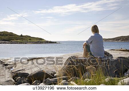 Woman sitting and looking out to sea View Large Photo Image Stock Photograph - Woman sitting and looking out to sea. Fotosearch