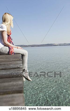 Stock Photography - Woman sitting on a landing stage. Fotosearch