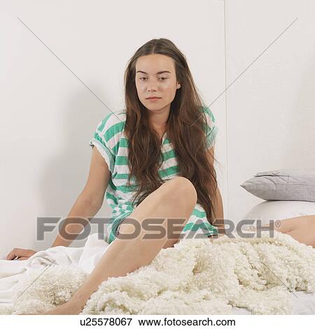 Stock Photo - Woman sitting on bed. Fotosearch