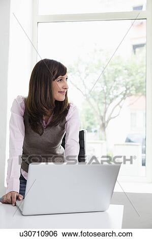 Woman standing in front of laptop View Large Photo Image Stock Photograph - Woman standing in front of laptop. Fotosearch