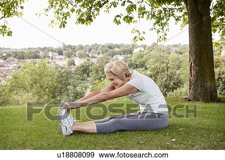 Woman stretching hands to toes in park View Large Photo Image Stock Photo - Woman stretching hands to toes in park. Fotosearch