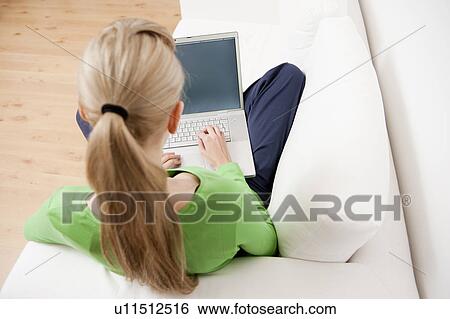 Woman using laptop on sofa View Large Photo Image Stock Photograph - Woman using laptop on sofa. Fotosearch