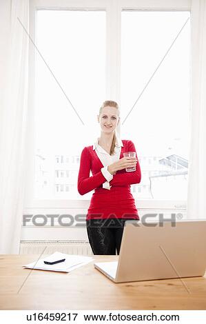 Stock Photo - Woman using laptop while drinking water. Fotosearch