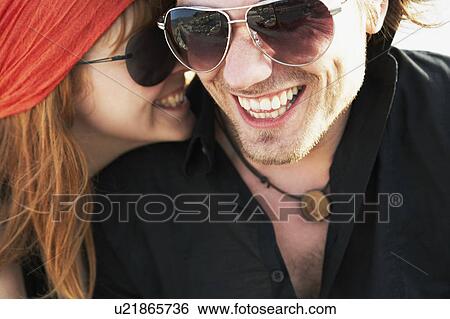Stock Photograph - Woman whispering man in to ear. Fotosearch