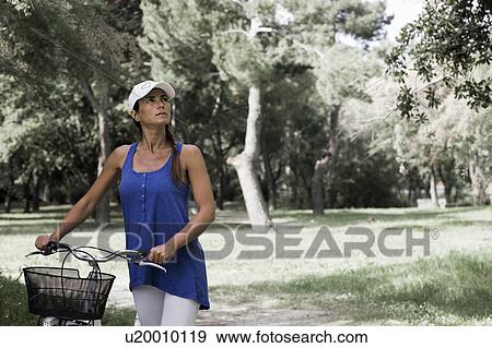 Stock Photo - Woman with a bike in a park. Fotosearch