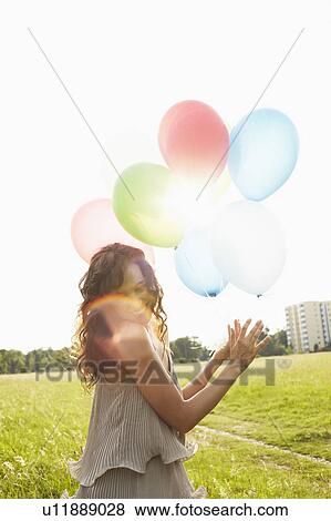 Stock Photo - Woman with air balloons in meadows. Fotosearch