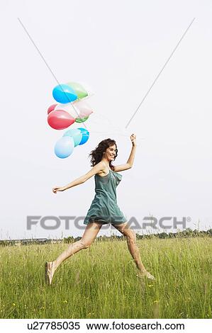 Stock Photography - Woman with air balloons jumping. Fotosearch