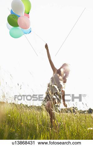 Woman with air balloons walking in field View Large Photo Image Stock Image - Woman with air balloons walking in field. Fotosearch