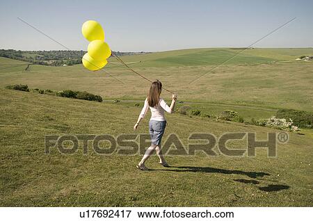 Woman with balloons walks down hill View Large Photo Image Stock Photo - Woman with balloons walks down hill. Fotosearch