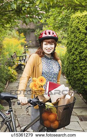 Stock Photo - Woman with bike and shoppingbasket. Fotosearch