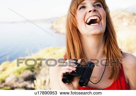 Stock Image - Woman with binoculars laughing. Fotosearch
