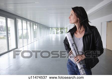 Stock Photo - Woman with blue prints, in an empty room. Fotosearch