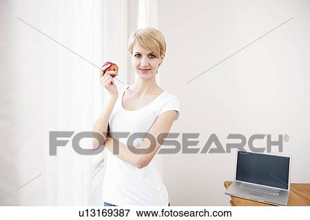 Woman with laptop and eating an apple View Large Photo Image Stock Photo - Woman with laptop and eating an apple. Fotosearch